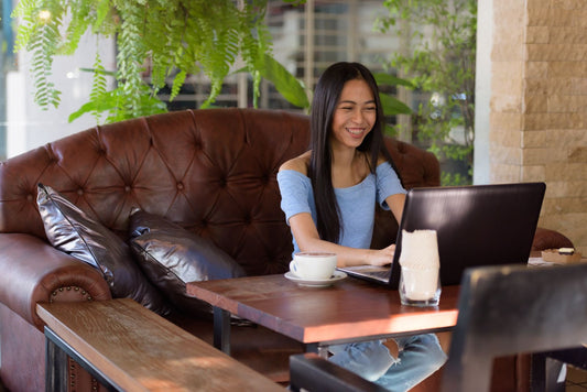 woman sitting on leather couch using laptop
