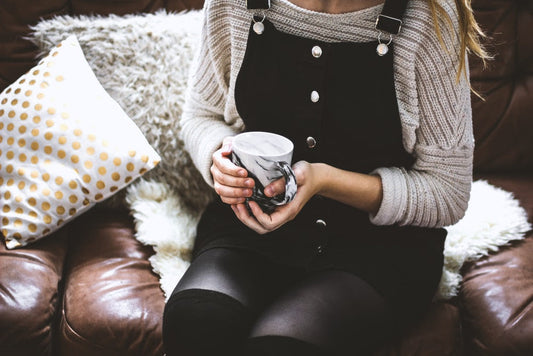 woman holding coffee sitting on couch