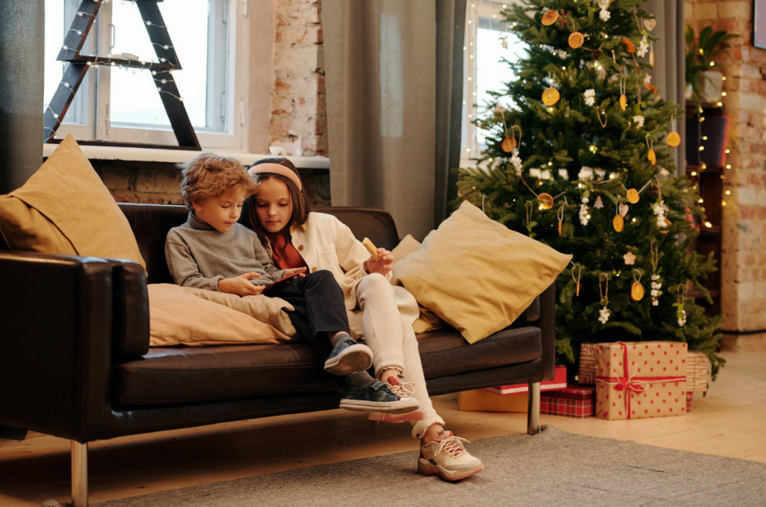 Kids on leather couch next to christmas tree