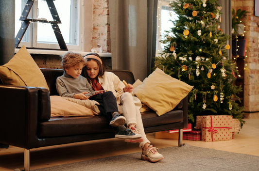 Kids on leather couch next to christmas tree