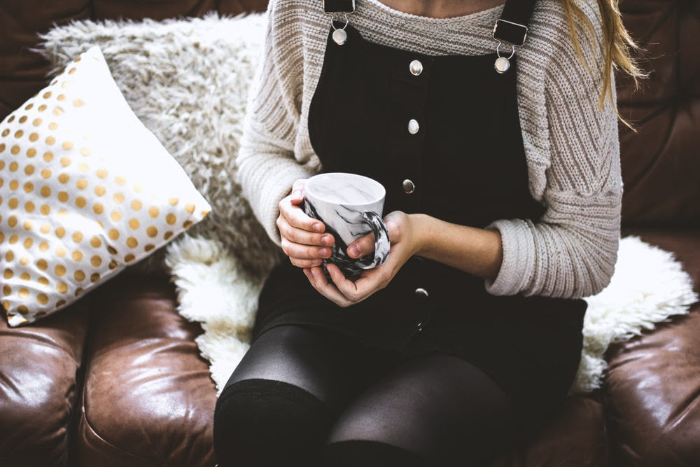 woman holding coffee sitting on couch